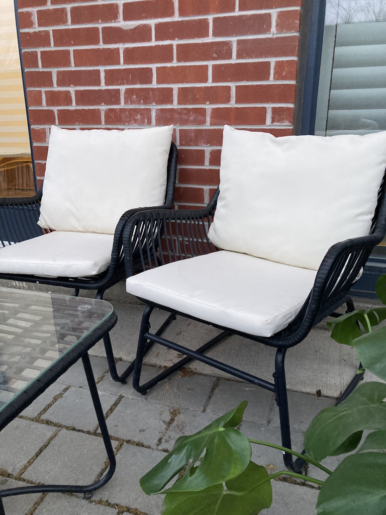 Two outdoor chairs and glass covered table