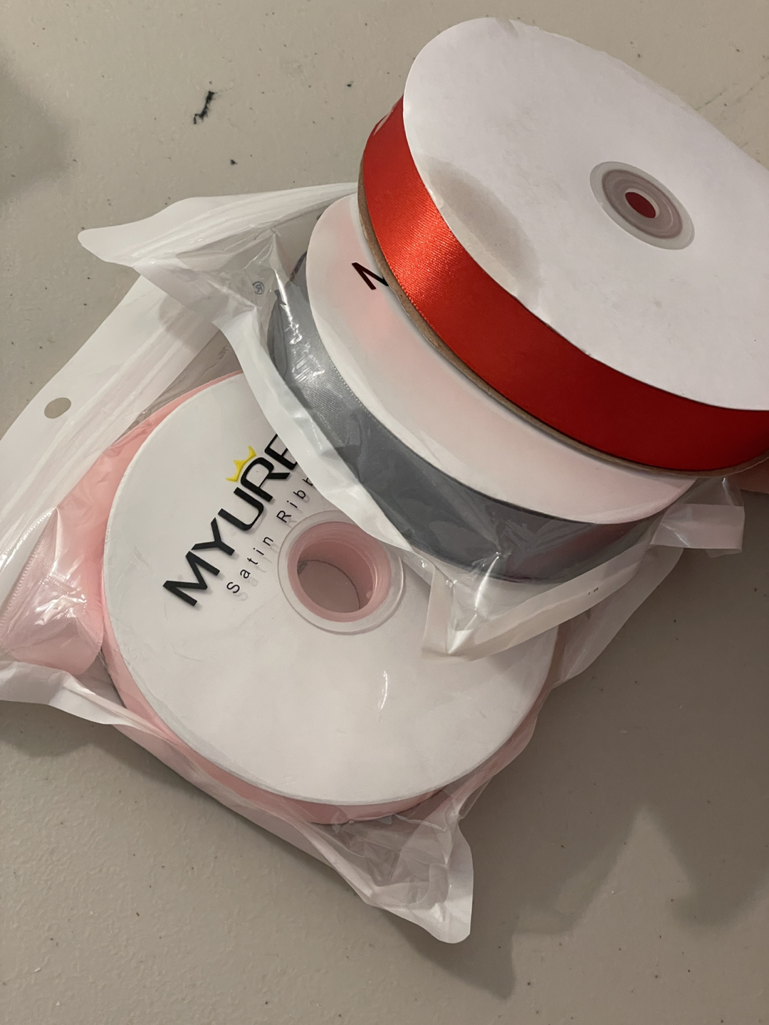 3 rolls of ribbon, grey, red, pink. 50 yards per roll