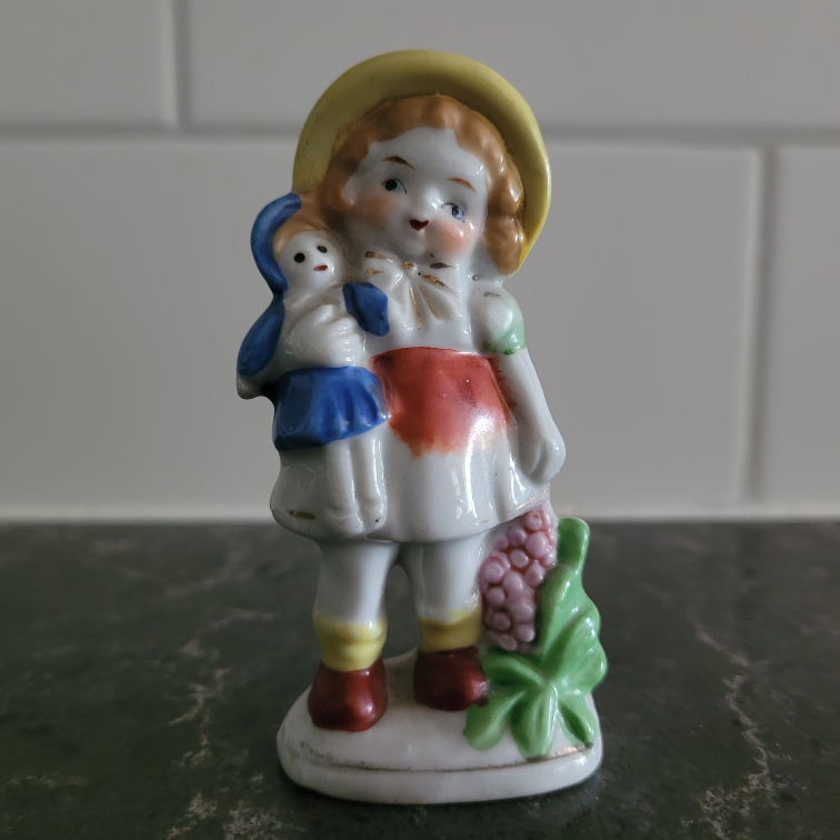 Girl holding doll and grapes figurine